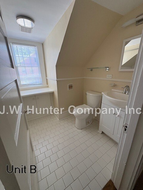 A bathroom with a toilet, sink and window.
