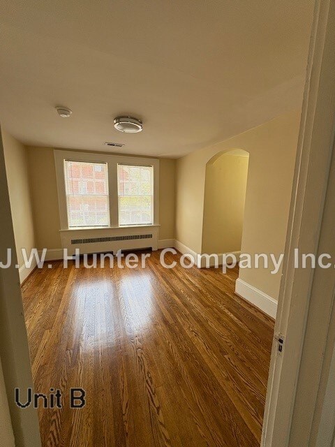 A room with wooden floors and a window with blinds.