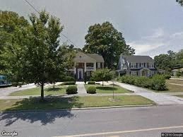 A street view of a residential area with houses and trees.