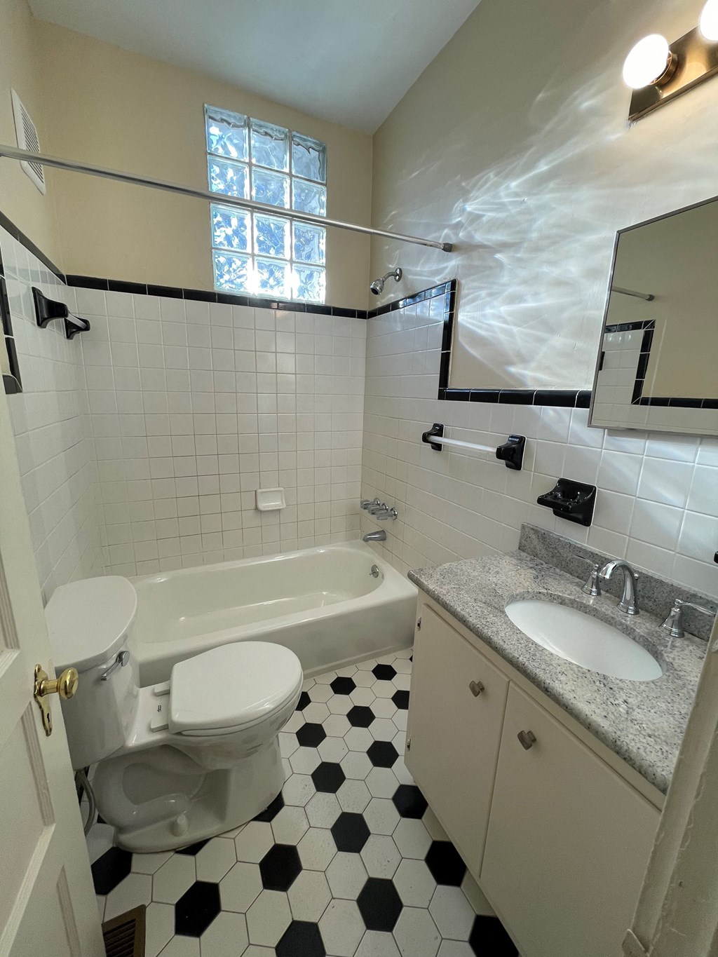 A white toilet with a white lid is in a bathroom with black and white tiles.