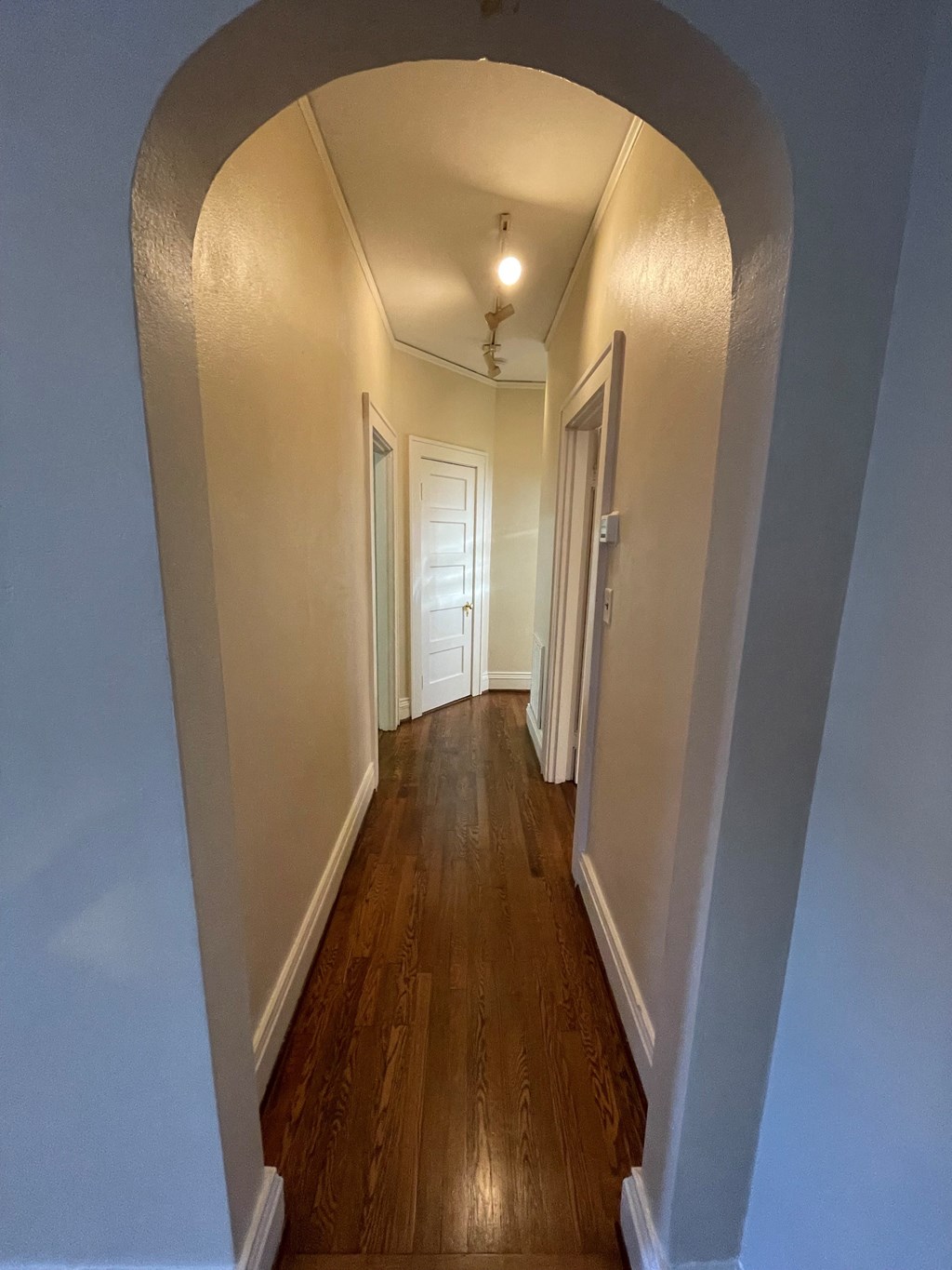 A long hallway with white walls and wood floors.
