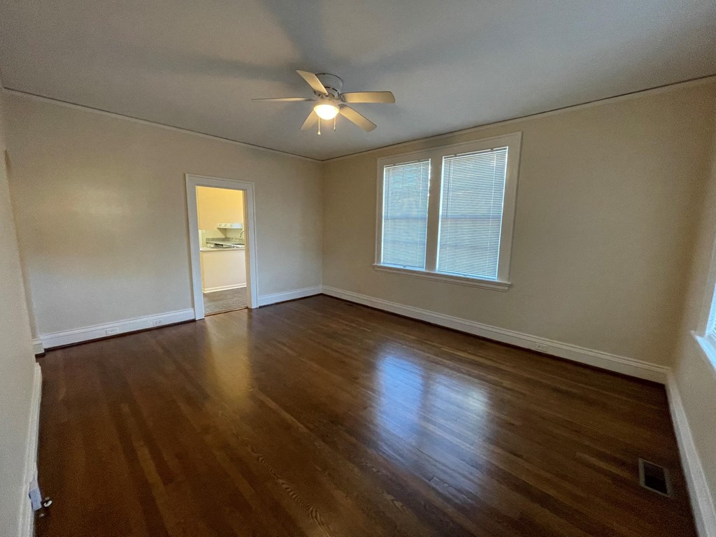 A room with a ceiling fan and wooden flooring.