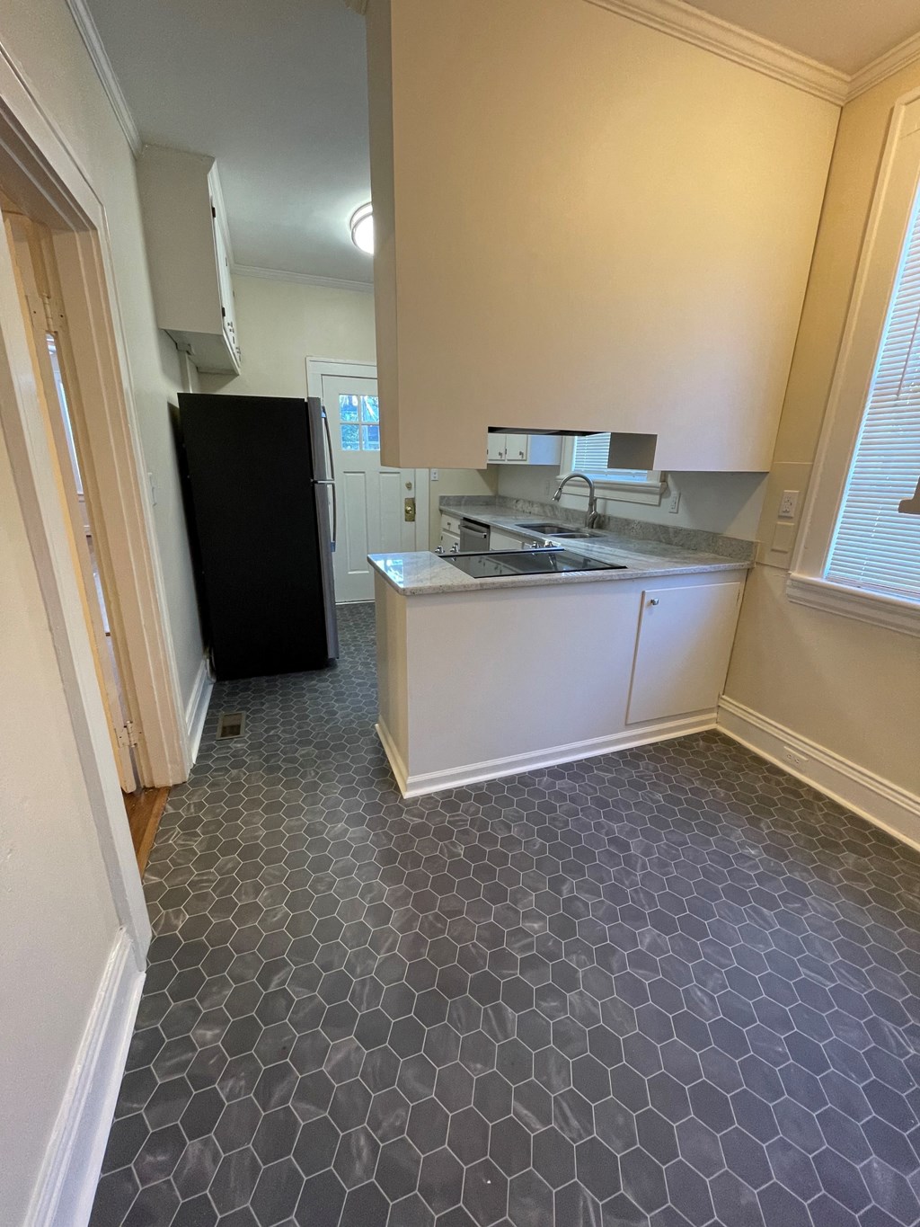 A kitchen with a black fridge and a white counter.