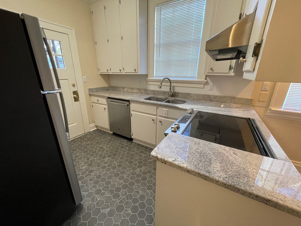 A kitchen with a black refrigerator and white cabinets.
