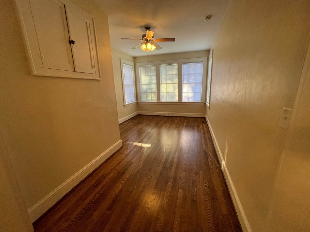 A long hallway with wood floors and a ceiling fan.