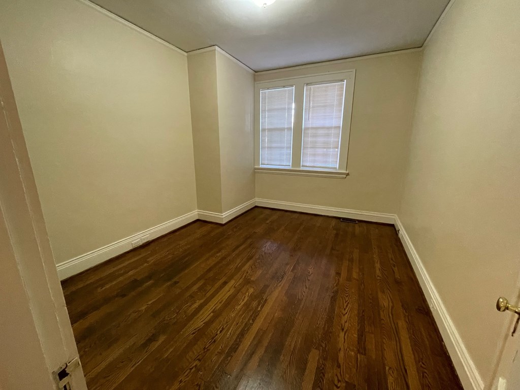 A room with wooden floors and a window with blinds.