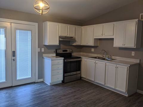 A kitchen with white cabinets and a wooden floor.