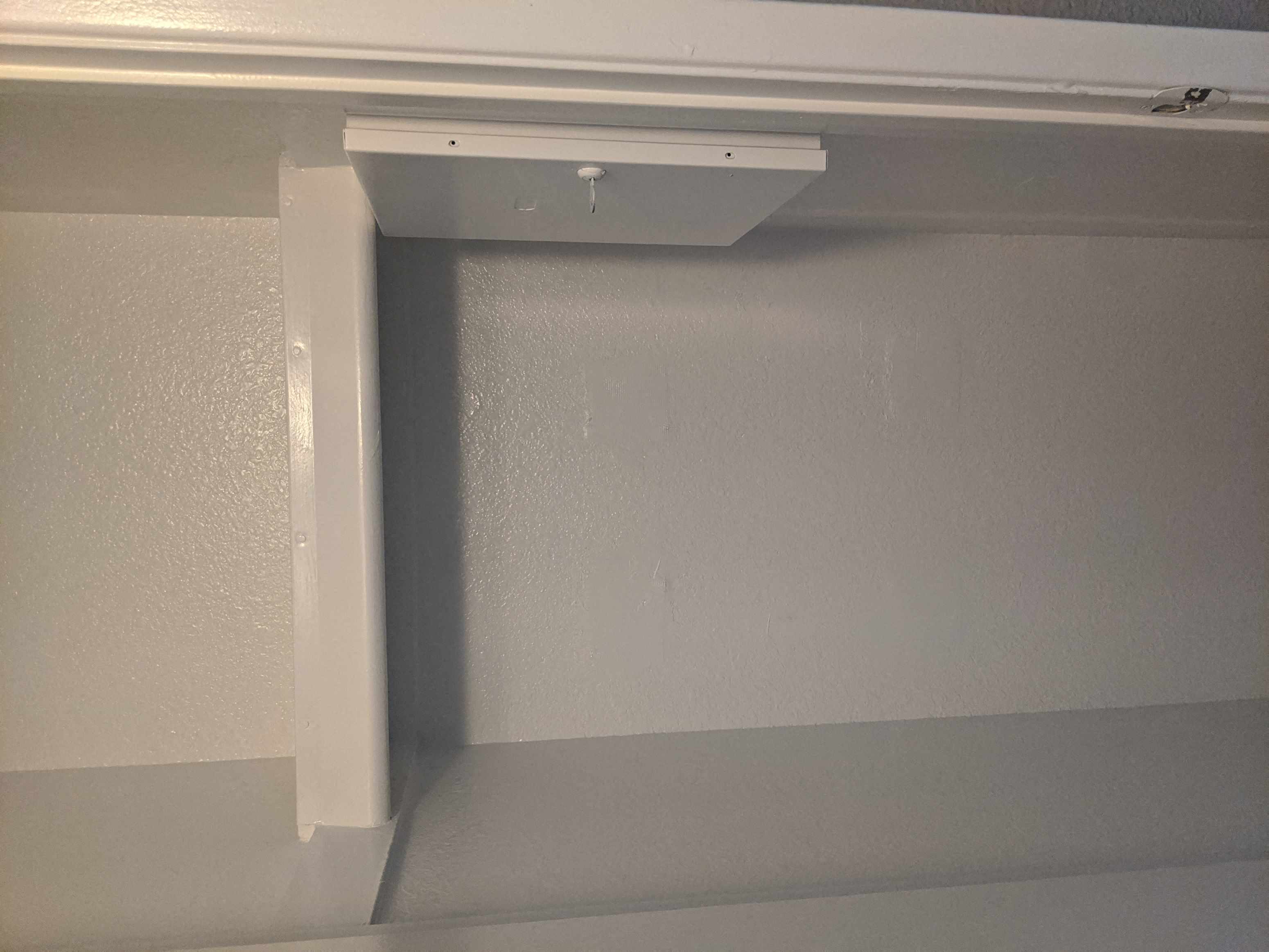 A white shelf bracket is mounted on a white wall.