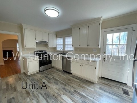A kitchen with white cabinets and a wooden floor.