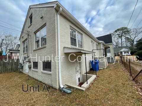 A two-story house with a white exterior and a blue trash can in front.