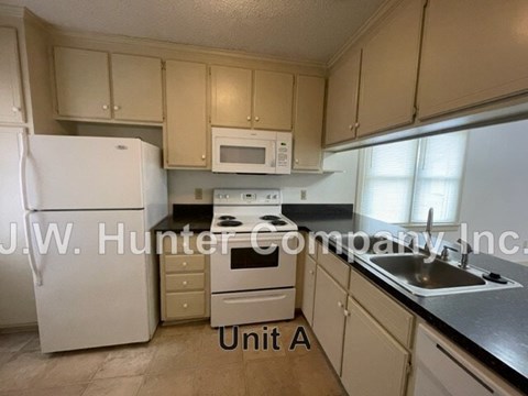 A kitchen with white appliances and beige cabinets.