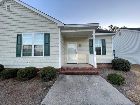 A house with a white door and green shutters.