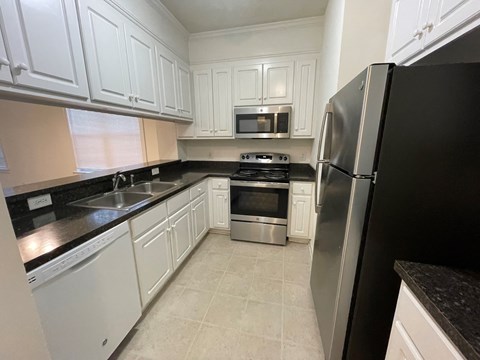 A kitchen with black countertops and white cabinets.
