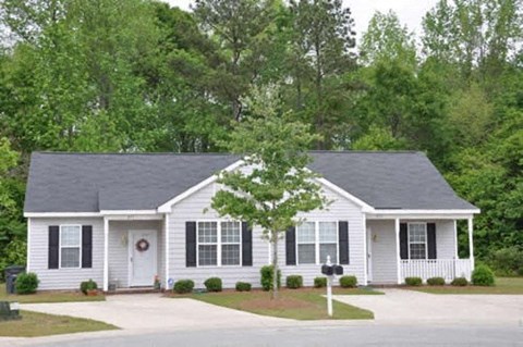 a white house with black shutters and a tree in front of it