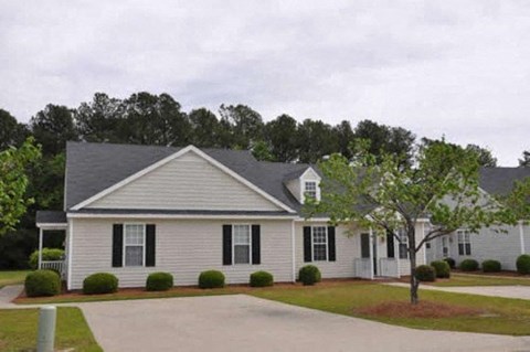 a white house with black shutters and a tree in the yard