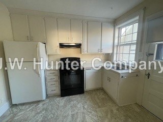 A kitchen with white cabinets and a black fridge.
