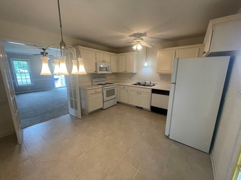 A kitchen with white appliances and cabinets.