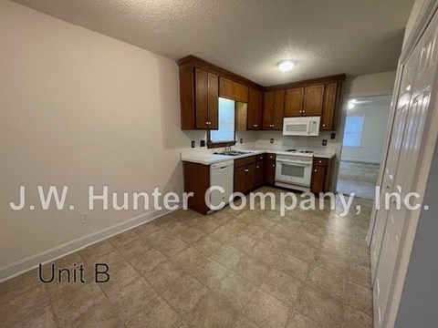 A kitchen with white appliances and wooden cabinets.