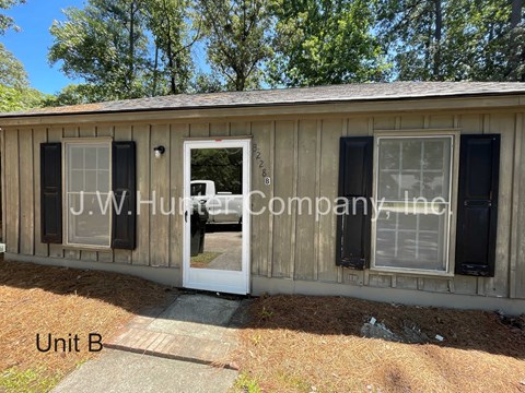 A wooden building with Unit B written on the ground in front of it.