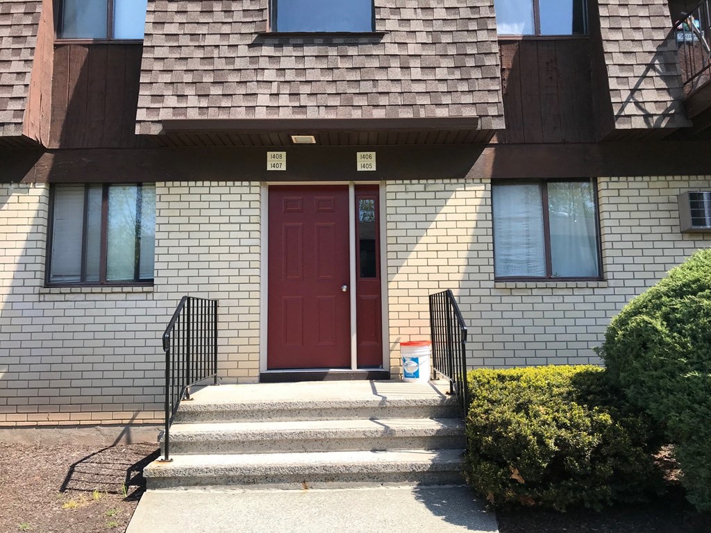 A red door is on the front of a brick building.