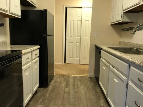 A kitchen with a black refrigerator and white cabinets.