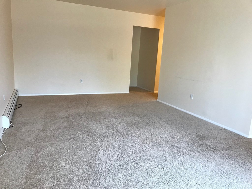 A room with a carpeted floor and a doorway leading to another room.