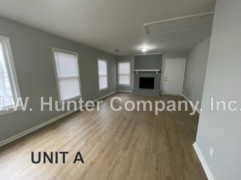 A spacious room with wood flooring and a fireplace, labeled as Unit A.