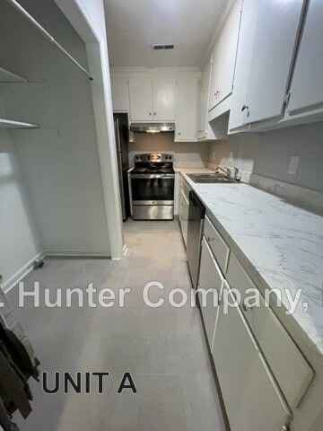 A kitchen with white cabinets and a stove top oven.