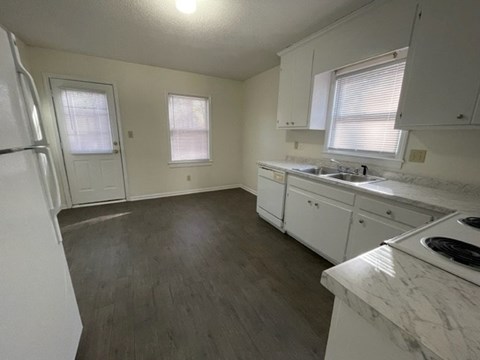 A kitchen with white cabinets and a marble countertop.