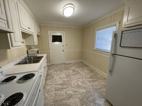 A kitchen with a white stove top oven and a white refrigerator.