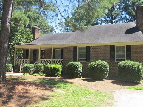 a brick house with a porch and some bushes