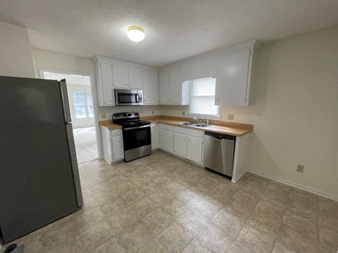 A kitchen with a black refrigerator and white cabinets.