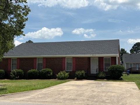 A red brick house with a grey roof and a white door.
