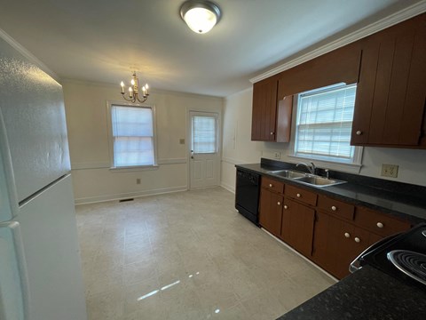 A kitchen with a black counter top and brown cabinets.