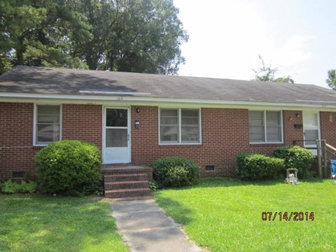 a brick house with a sidewalk in front of it