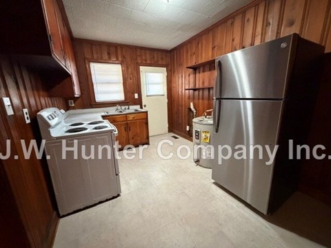 A kitchen with a stove, refrigerator, and sink.