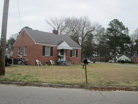 a red brick house with a yard and a mailbox