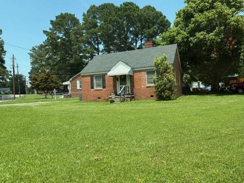 A small brick house with a green lawn in front.