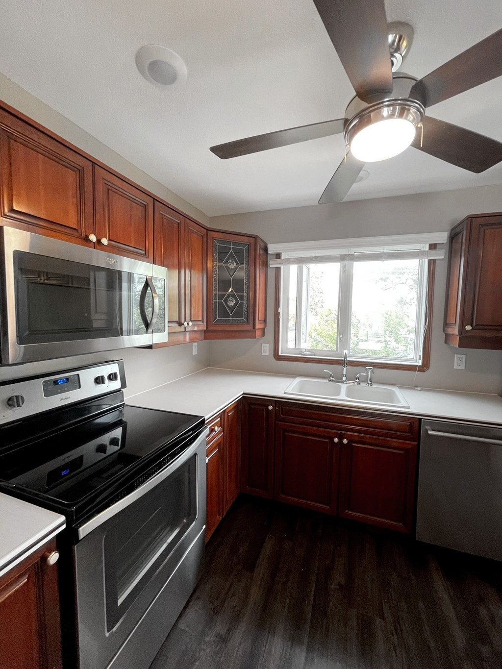 an empty kitchen with stainless steel appliances and wooden cabinets