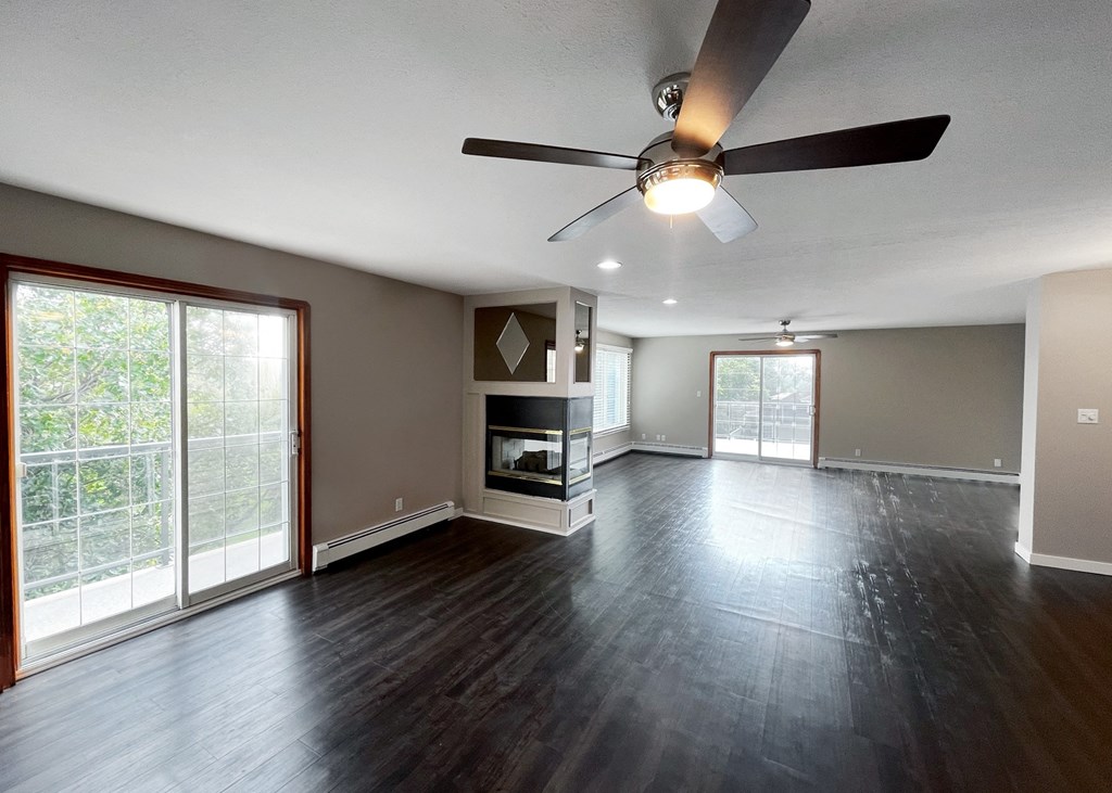 an empty living room with wood floors and a ceiling fan