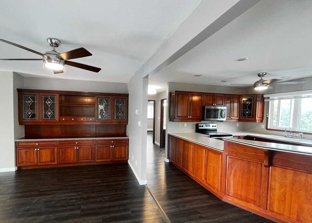 an empty kitchen with wooden cabinets and a ceiling fan