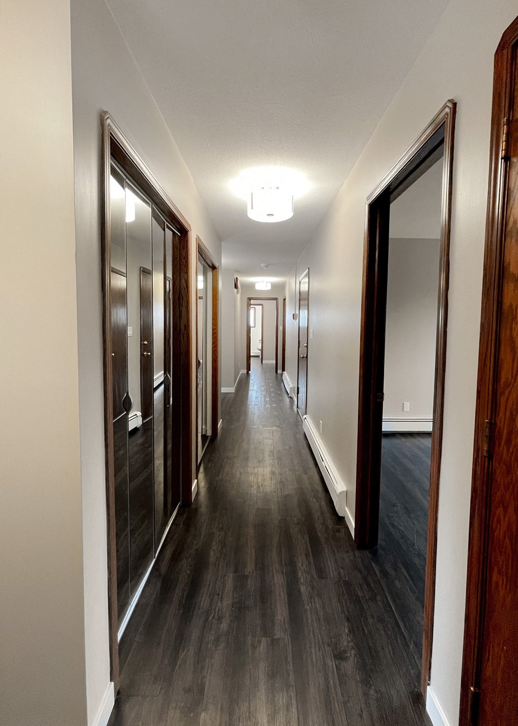 a hallway with mirrors and closets and a hall way with wood flooring
