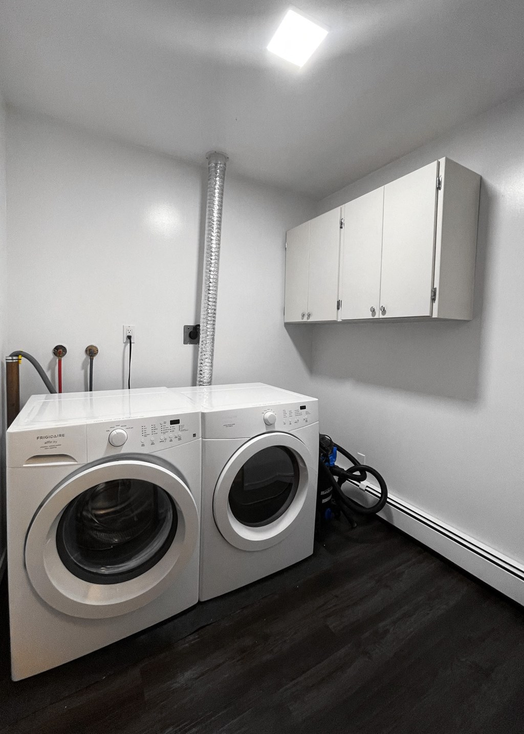 a white washer and dryer in a laundry room with white cabinets and a