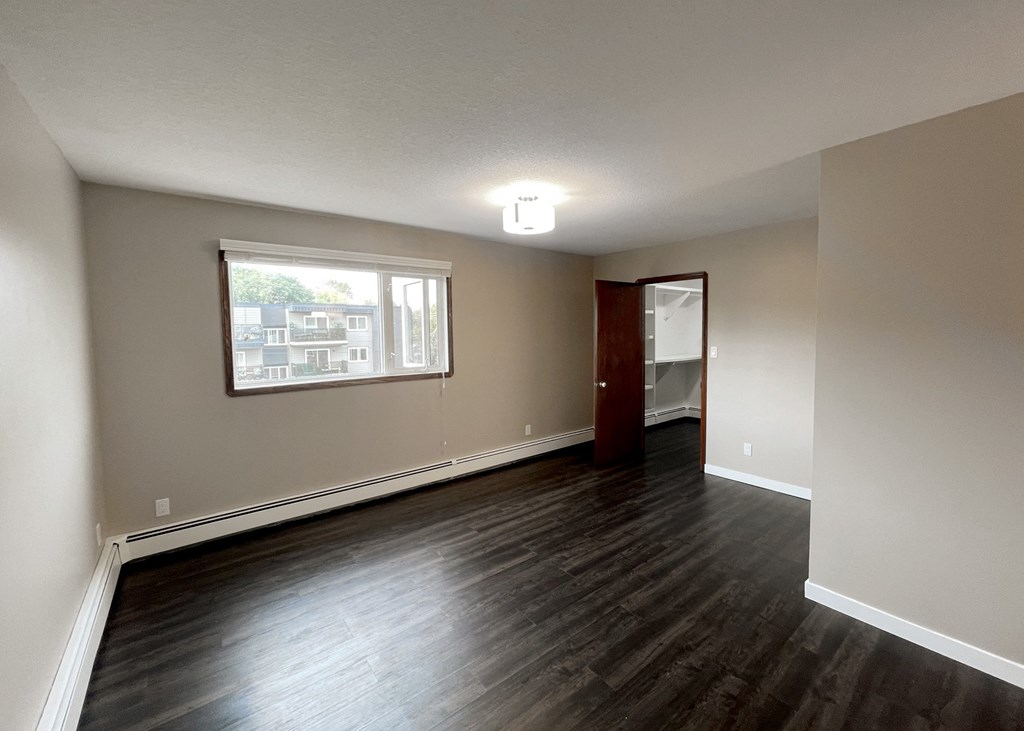 an empty living room with wood floors and a window