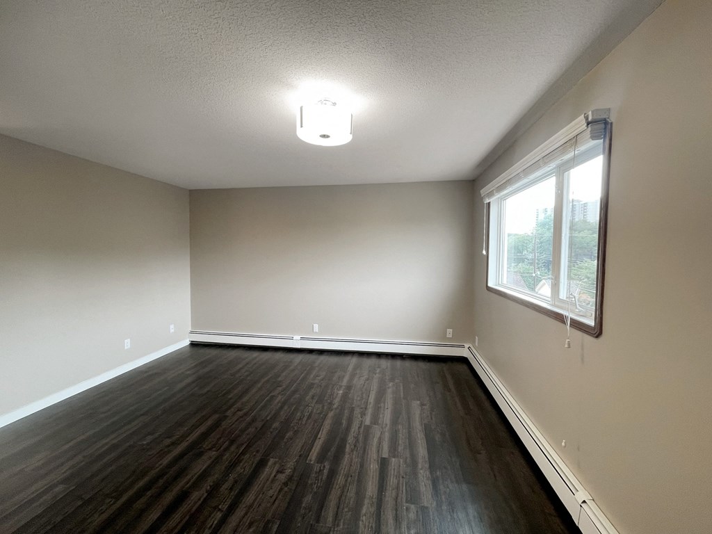 an empty living room with wood floors and a window