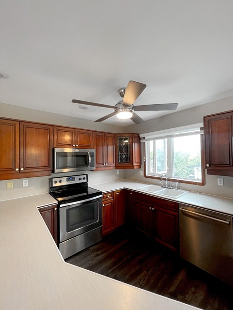 a kitchen with wooden cabinets and stainless steel appliances and a ceiling fan