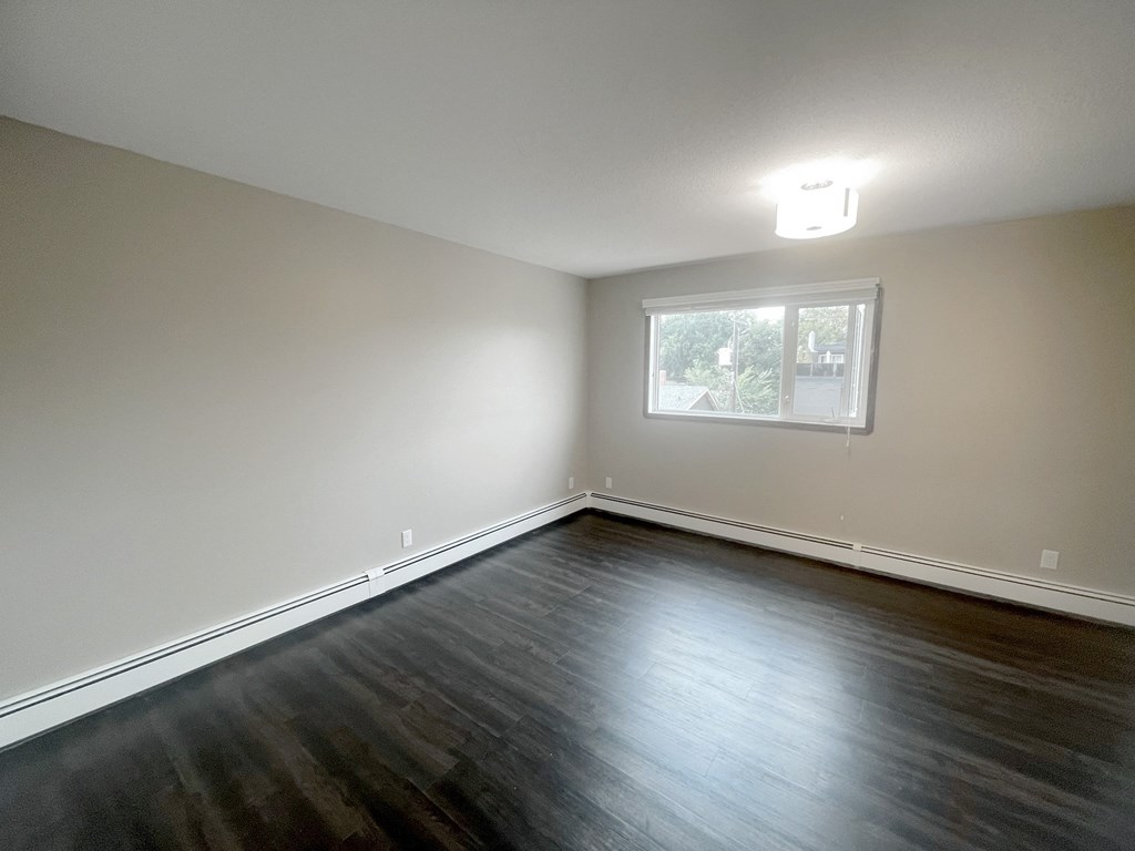 an empty living room with wood floors and a window
