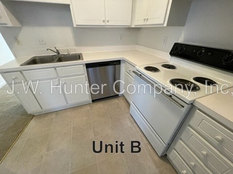 A kitchen with a stove, sink, and cabinets.