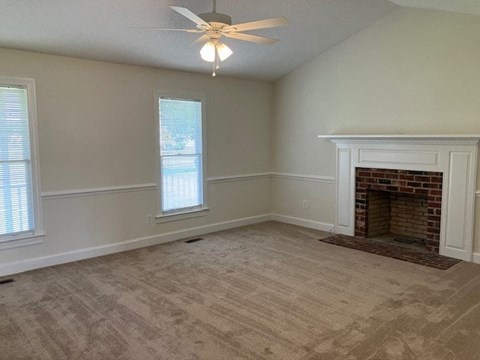 an empty living room with a fireplace and a ceiling fan