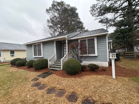 A house with a grey roof and a small front yard with a tree.
